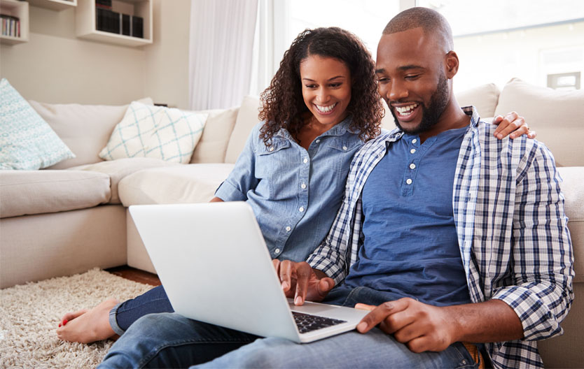 Photo of a smiling couple searching a laptop together
