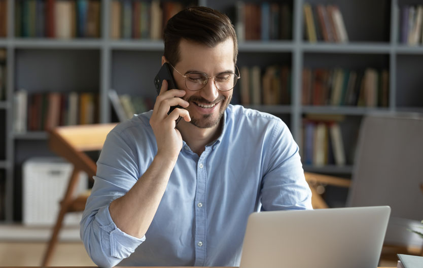 Photo of a smiling man at his desk on the phone