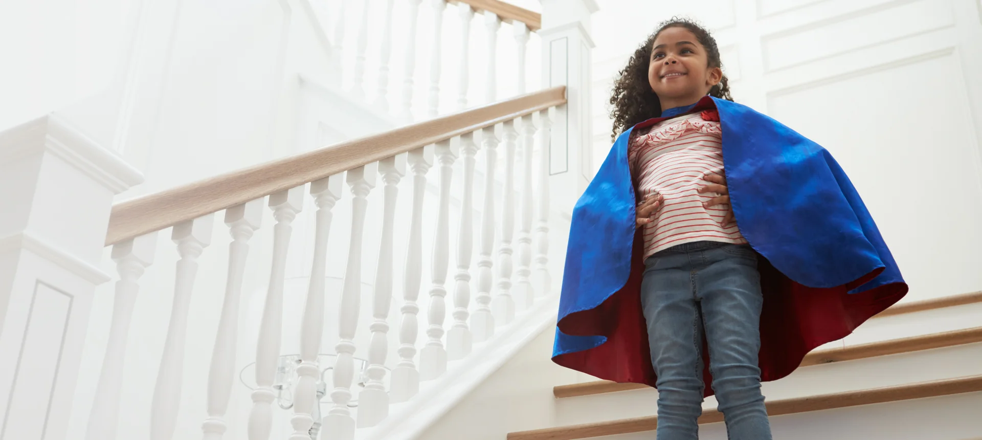 Photo of a young girl standing on some stairs wearing a cape