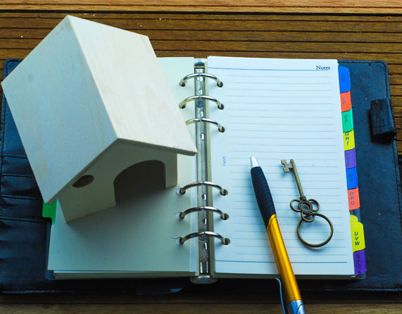 Image showing a model house on top of an open planner with a pen and a key next to it
